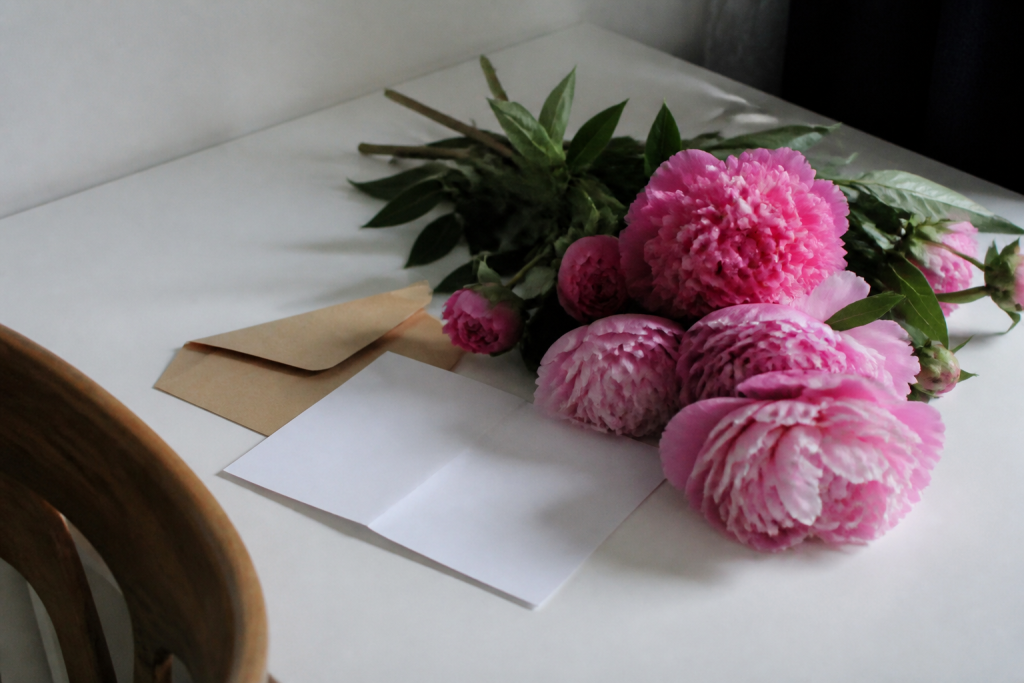 Fleurs roses avec lettre manuscrite sur table blanche