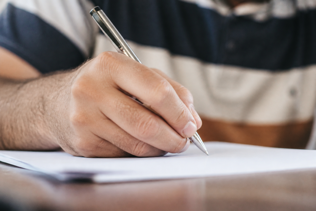 Gros plan main ecrivant avec stylo sur papier blanc