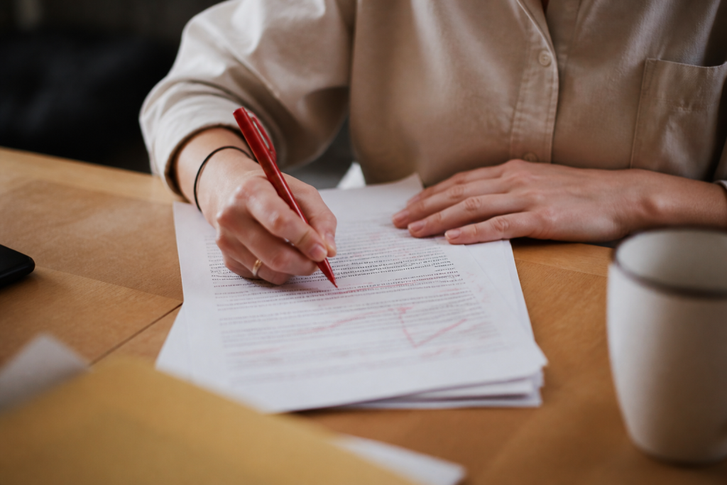 Main annotant document texte avec stylo rouge
